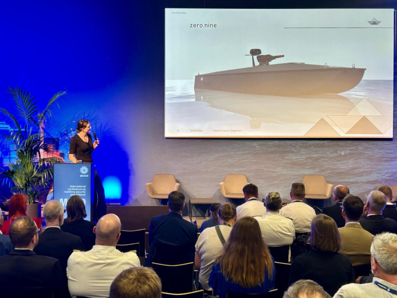 Diana S. Engelhard presenting on stage at MS&D 2024 during SMM Hamburg. zero.nine tactical swarm vessel shown on screen. BlackBoats founder and pioneer in maritime autonomy and tactical AI.
